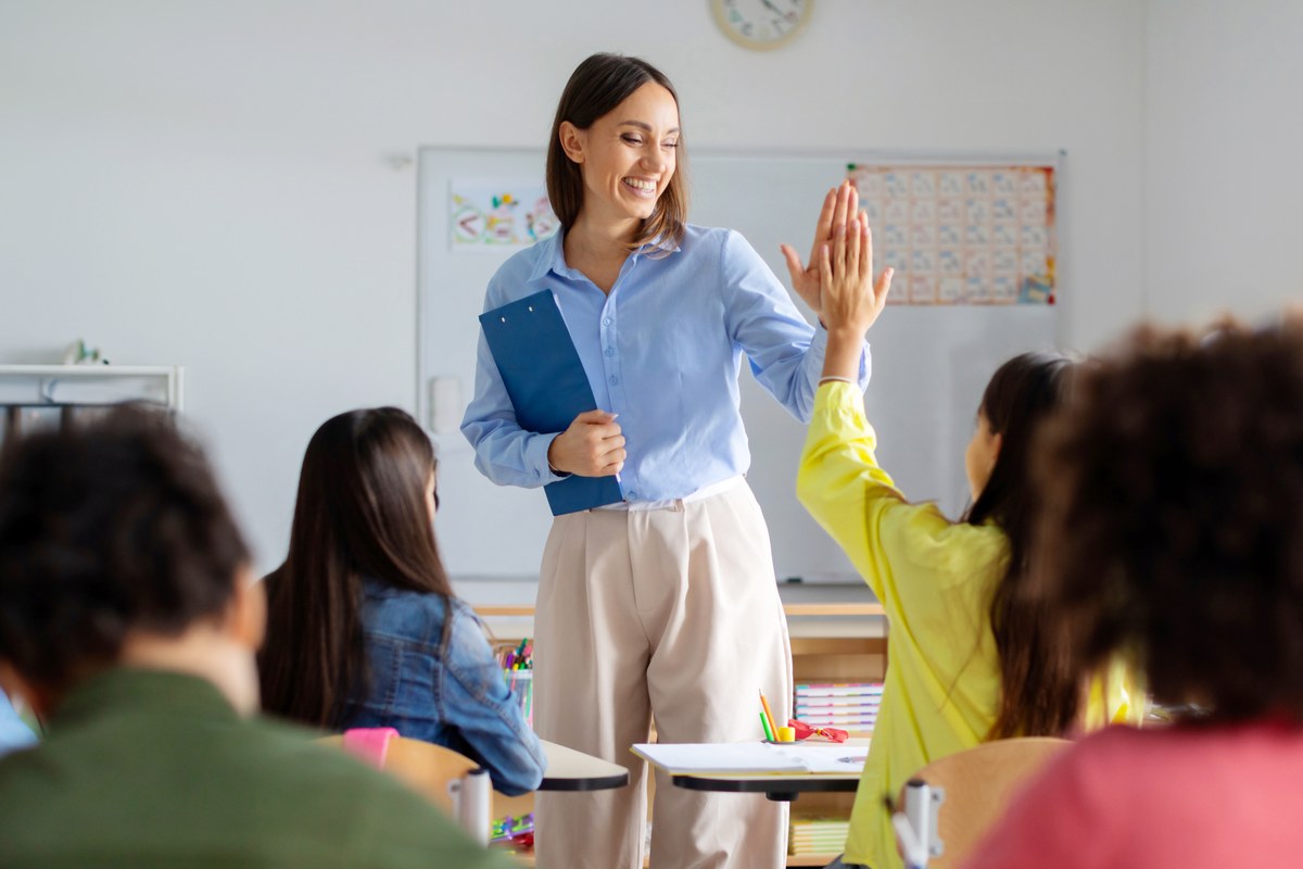 Teacher giving a high five to a pupil in a primary school classroom