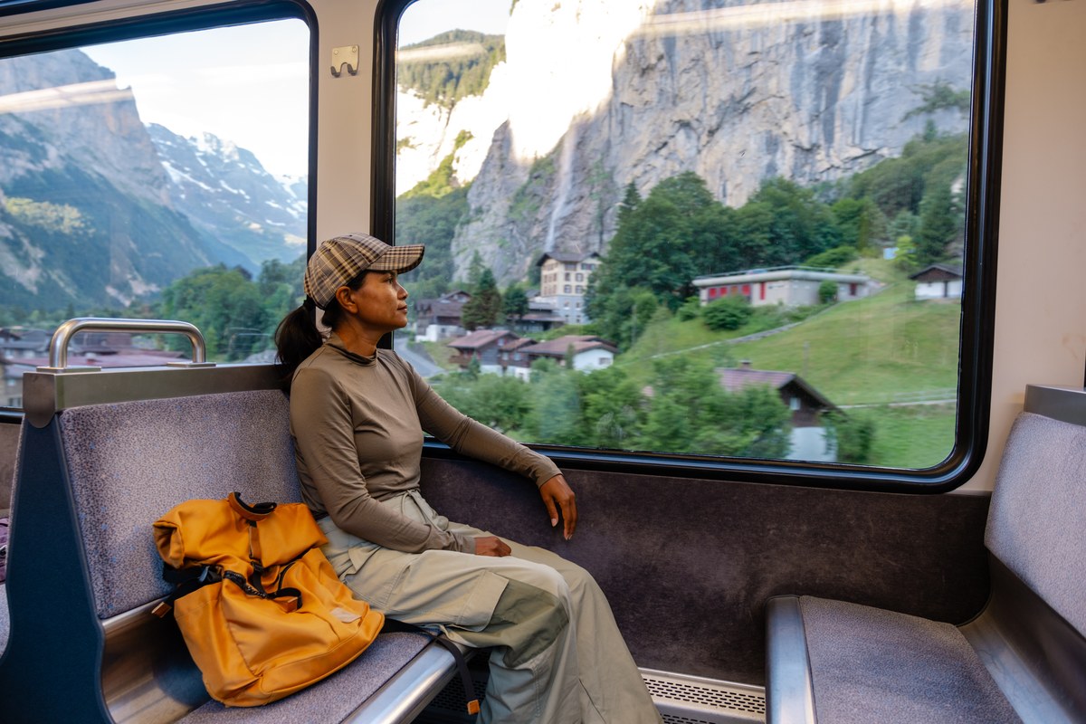 Woman looking out of a train window at the Lauterbrunnen valley cliffs