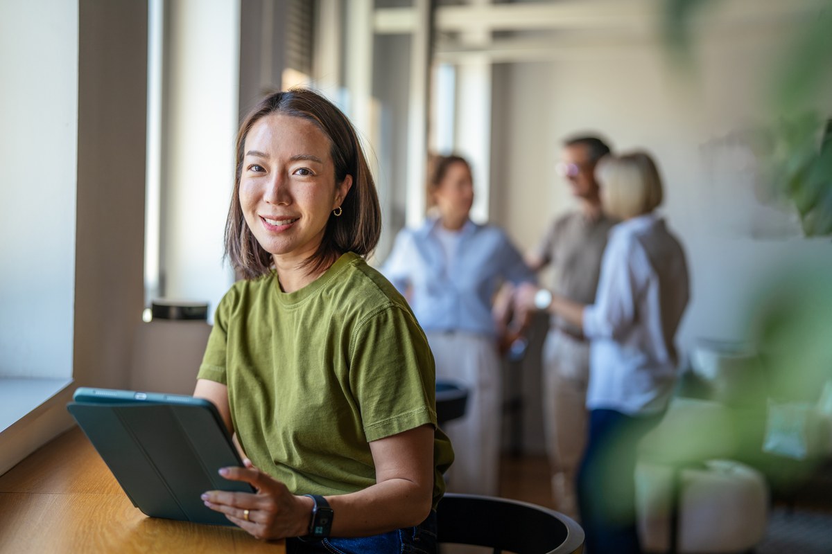Smiling woman with a tablet at a desk in a modern office