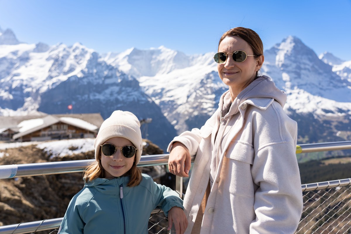 Woman and a child at a railing in front of snowy Alps near Grindelwald