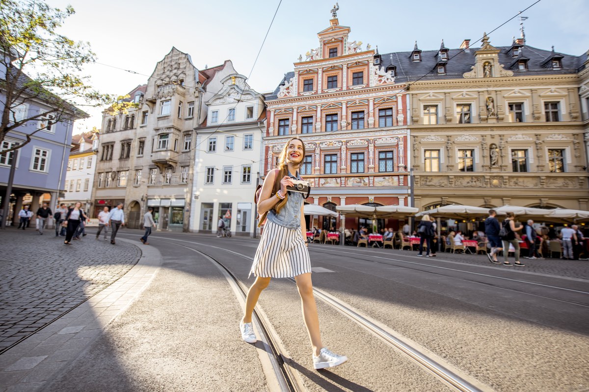 Young woman with a camera walking across a square in Erfurt's old town