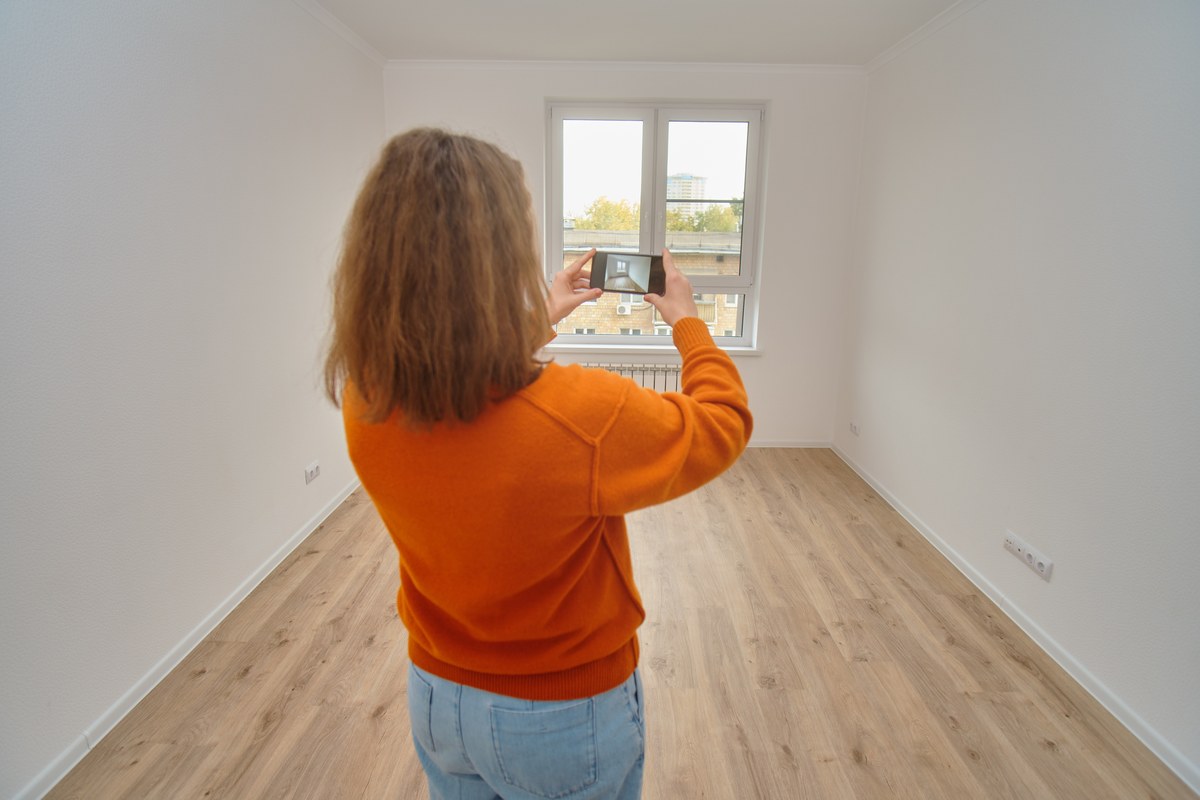 Woman photographing an empty apartment room with her phone
