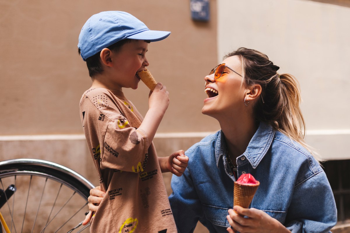 Laughing mother and young son eating ice cream on a city street