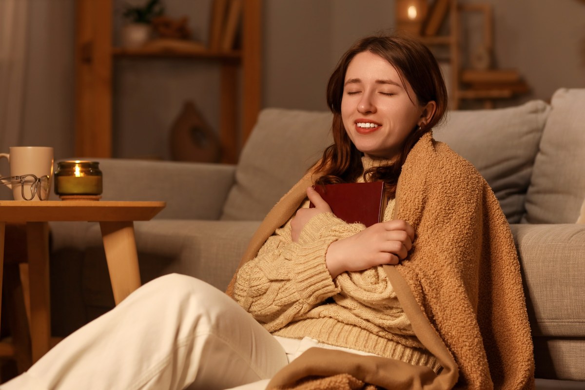 Woman relaxing under a blanket at home