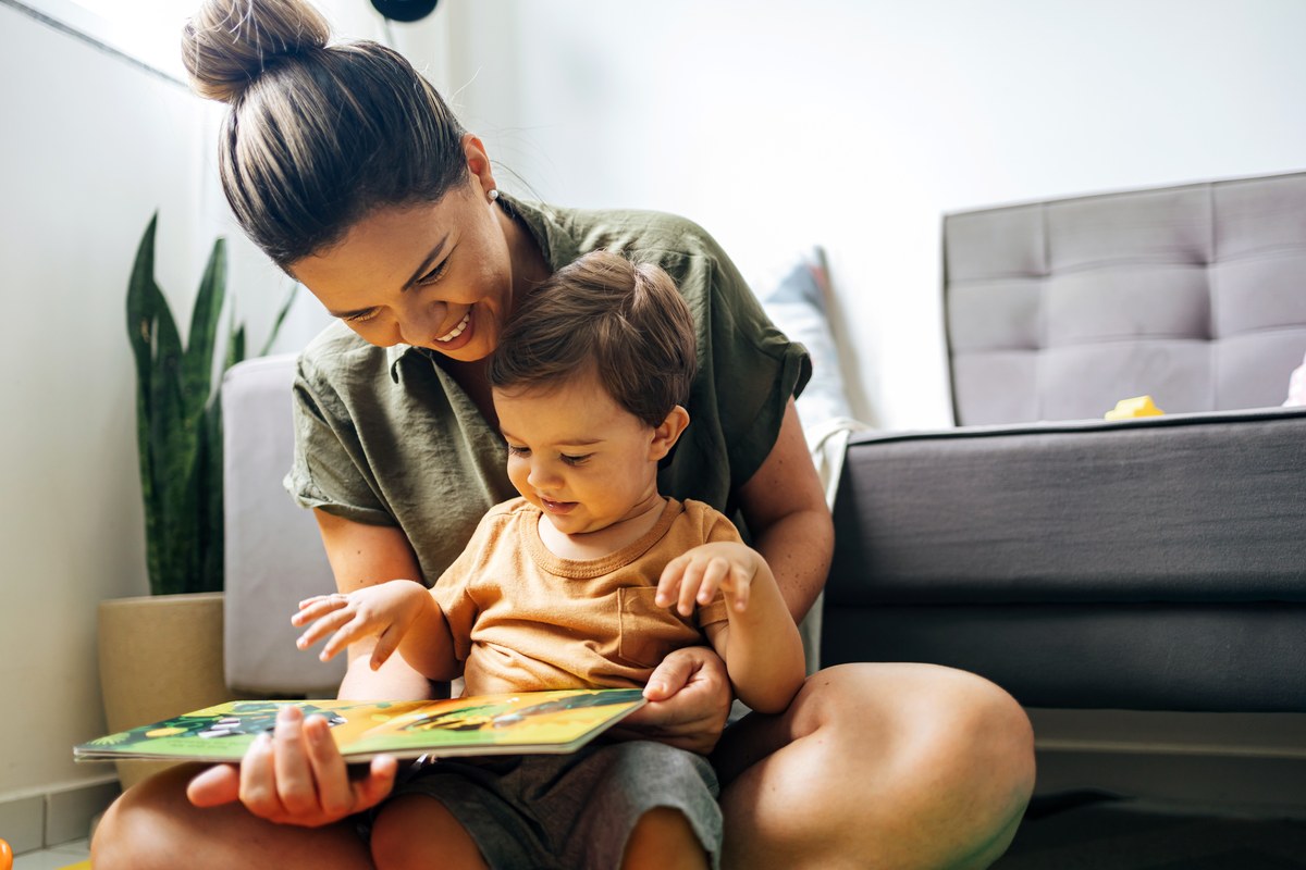 Mother reading a picture book with her toddler son at home