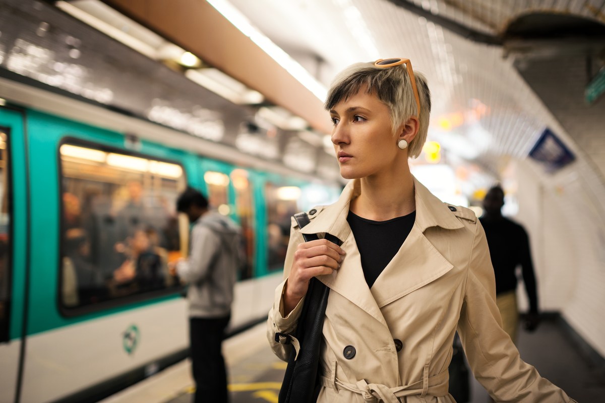 Woman in a trench coat on a Paris Métro platform beside a train
