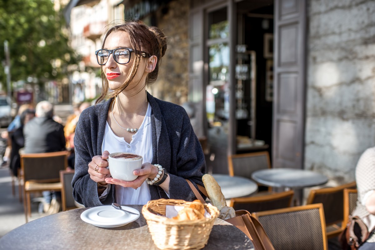 Woman drinking coffee with croissants at a café terrace in Lyon