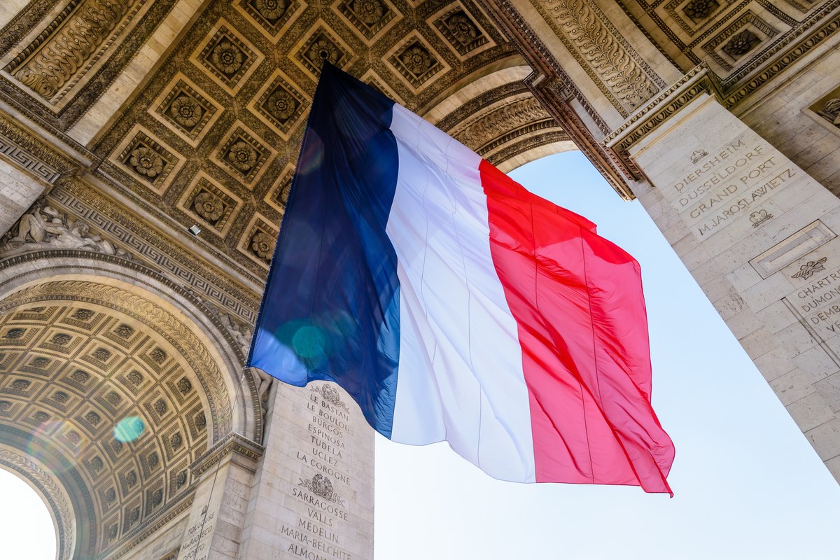 French flag hanging beneath the Arc de Triomphe in Paris