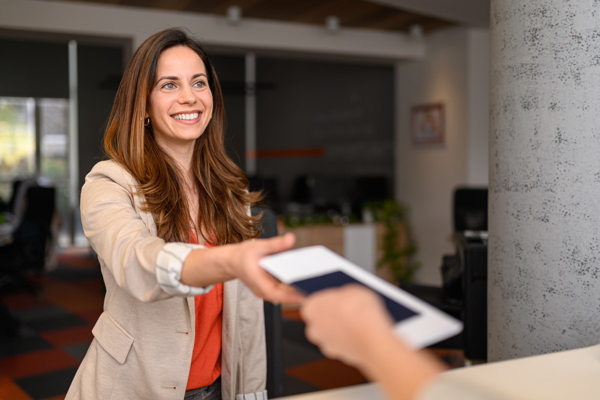 Smiling woman handing her passport across a counter