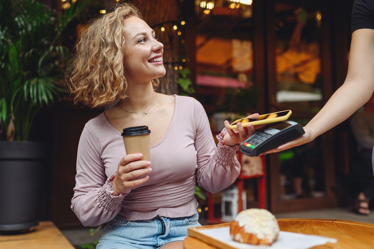 Woman in a café paying with her phone at a card terminal