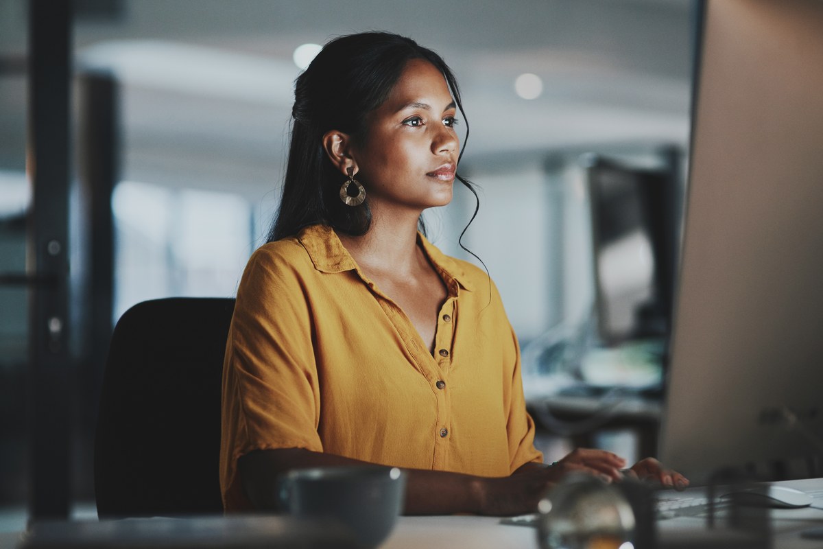 Woman in a mustard blouse working at a computer in an office