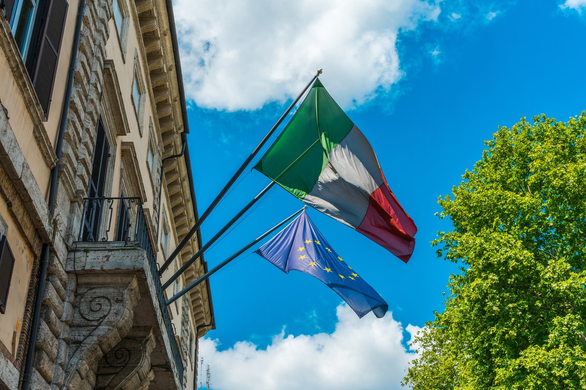 Italian and European Union flags flying from a historic building