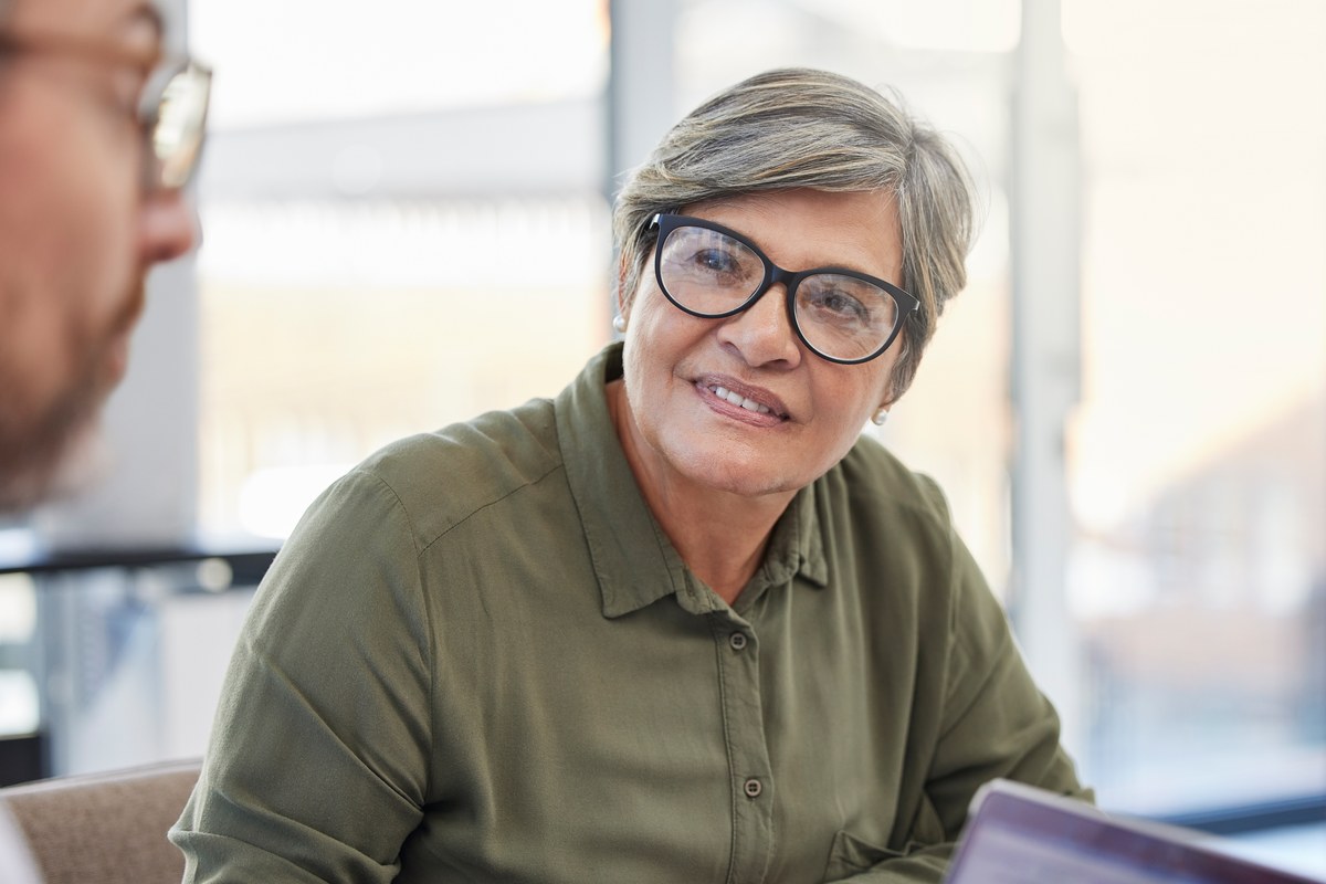 Smiling older woman with glasses in a meeting at an office