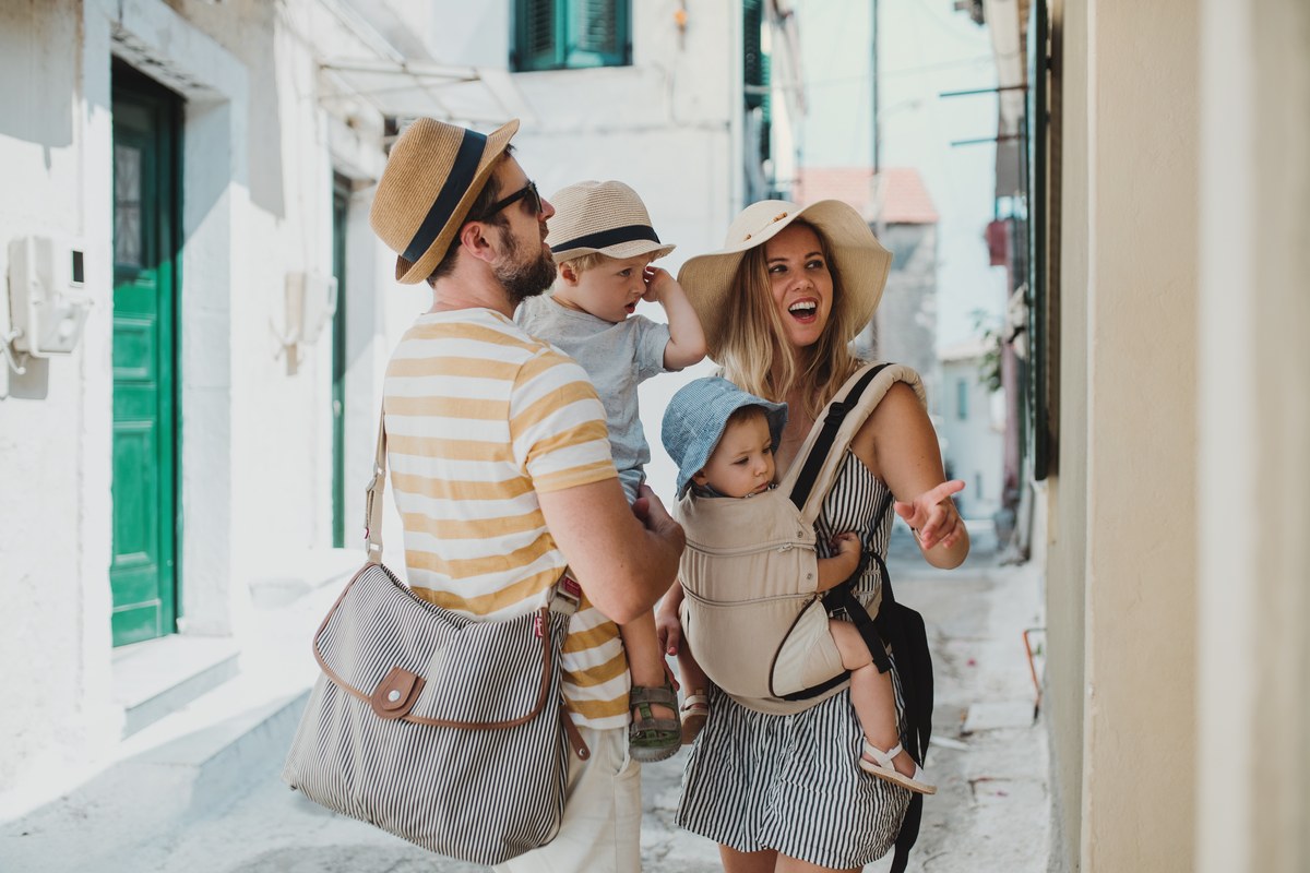 Mother carrying a baby and father holding a toddler in a narrow whitewashed street