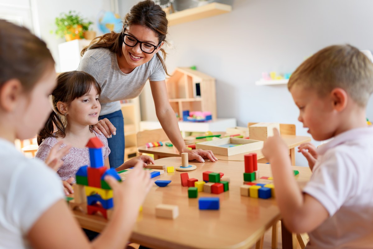 Teacher playing with children at kindergarten