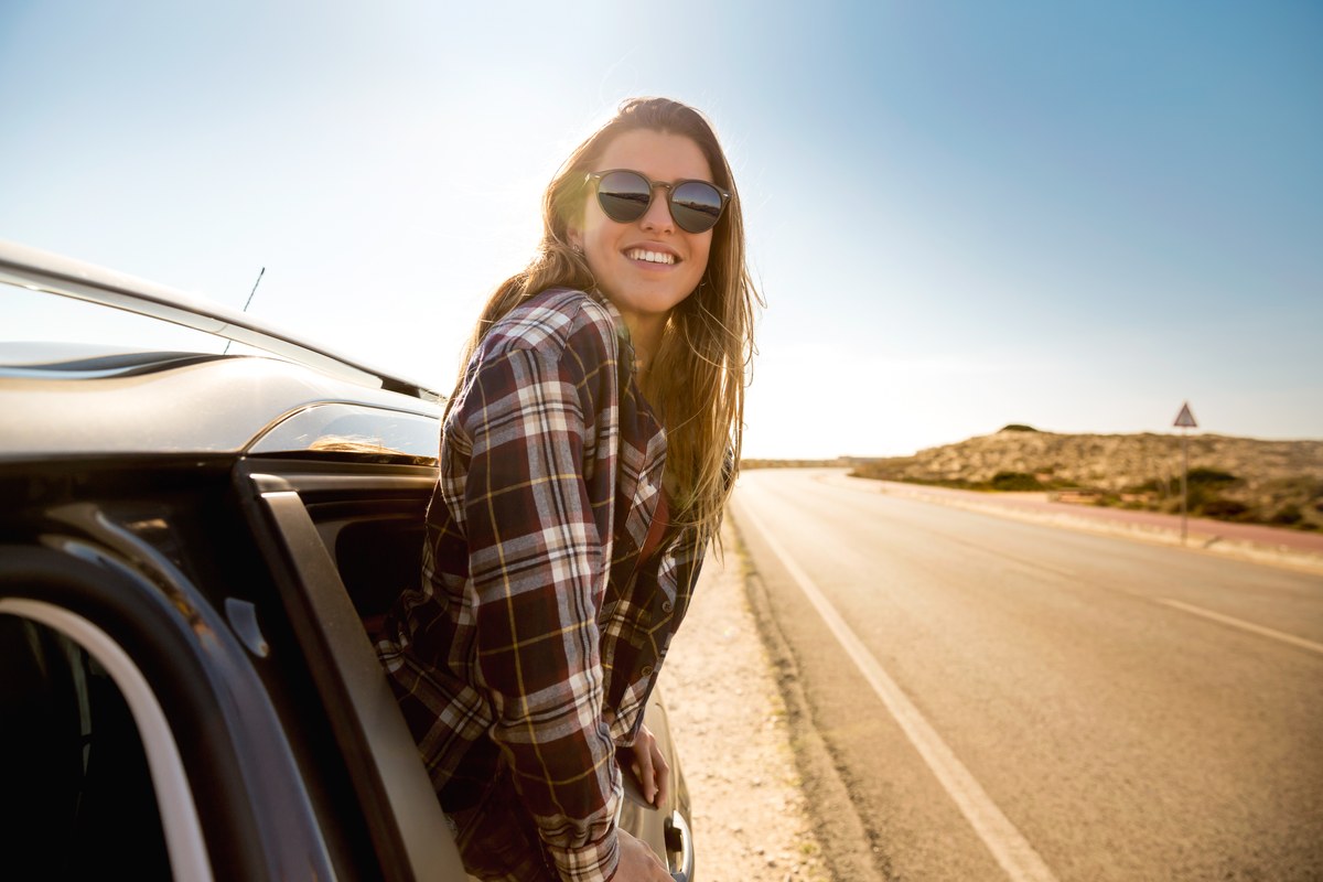 Woman by her car on an open road