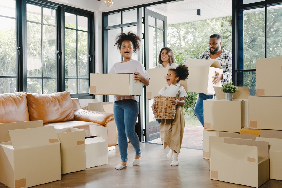Family carrying moving boxes into their new home