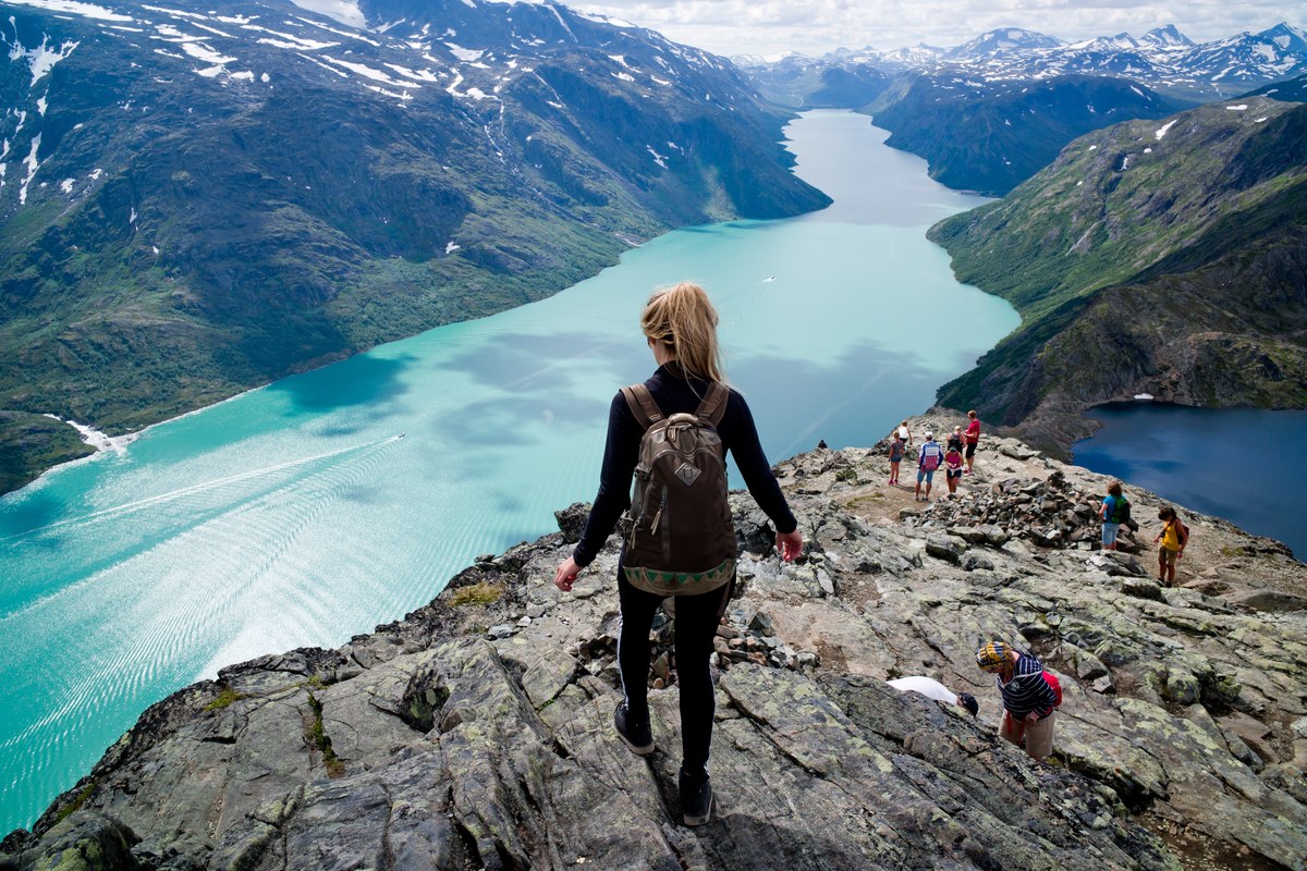 Hiker above a turquoise mountain lake in Norway