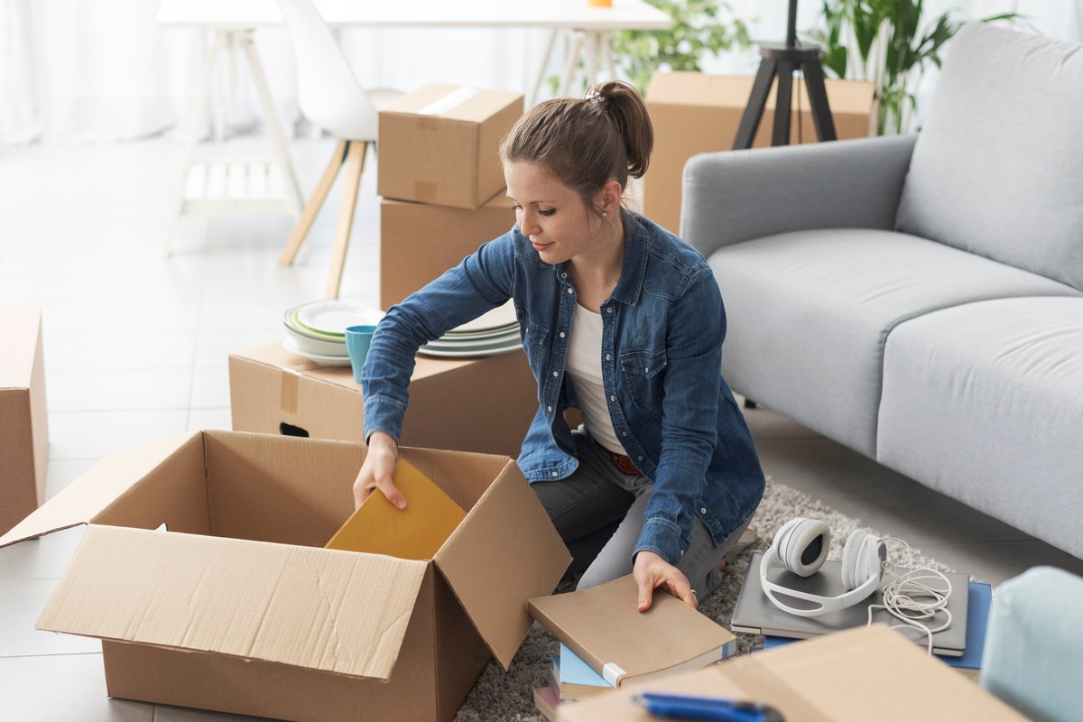 Woman unpacking cardboard moving boxes in a bright living room