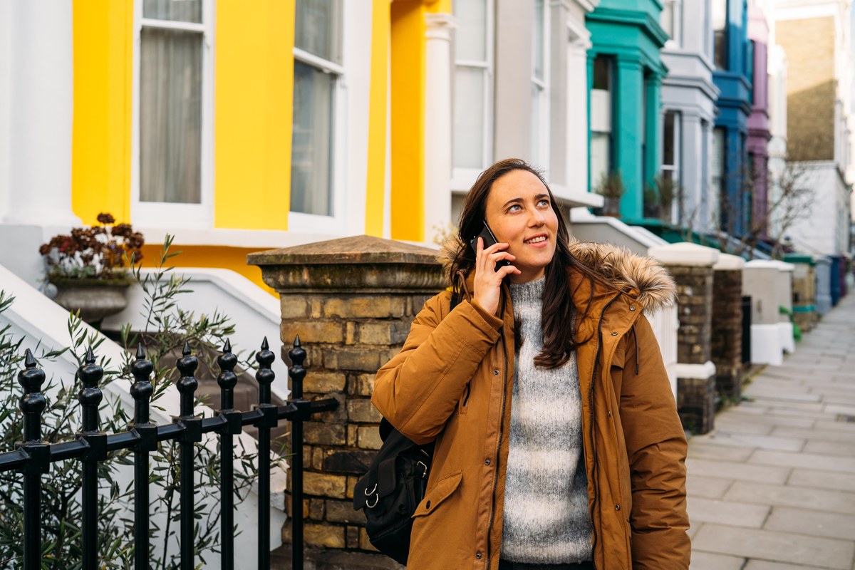 Woman on the phone by colourful terraced houses in Notting Hill, London