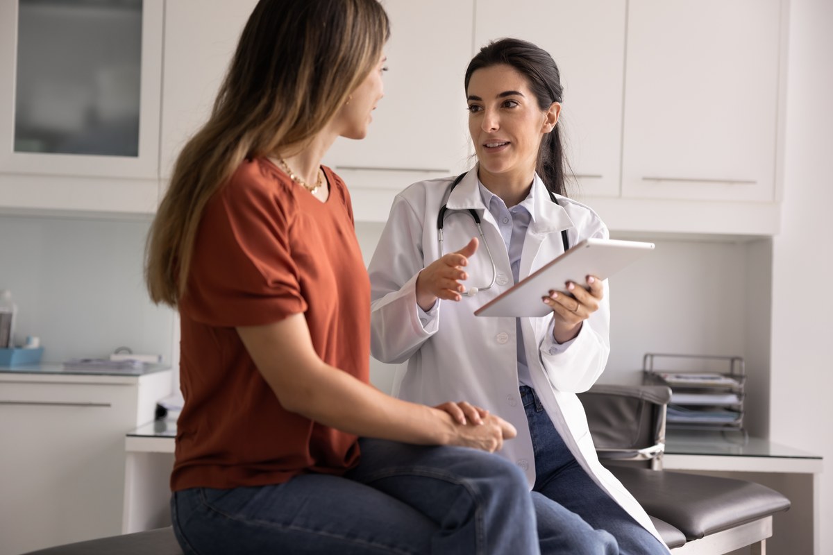 Woman patient talking with a female doctor holding a tablet in a clinic