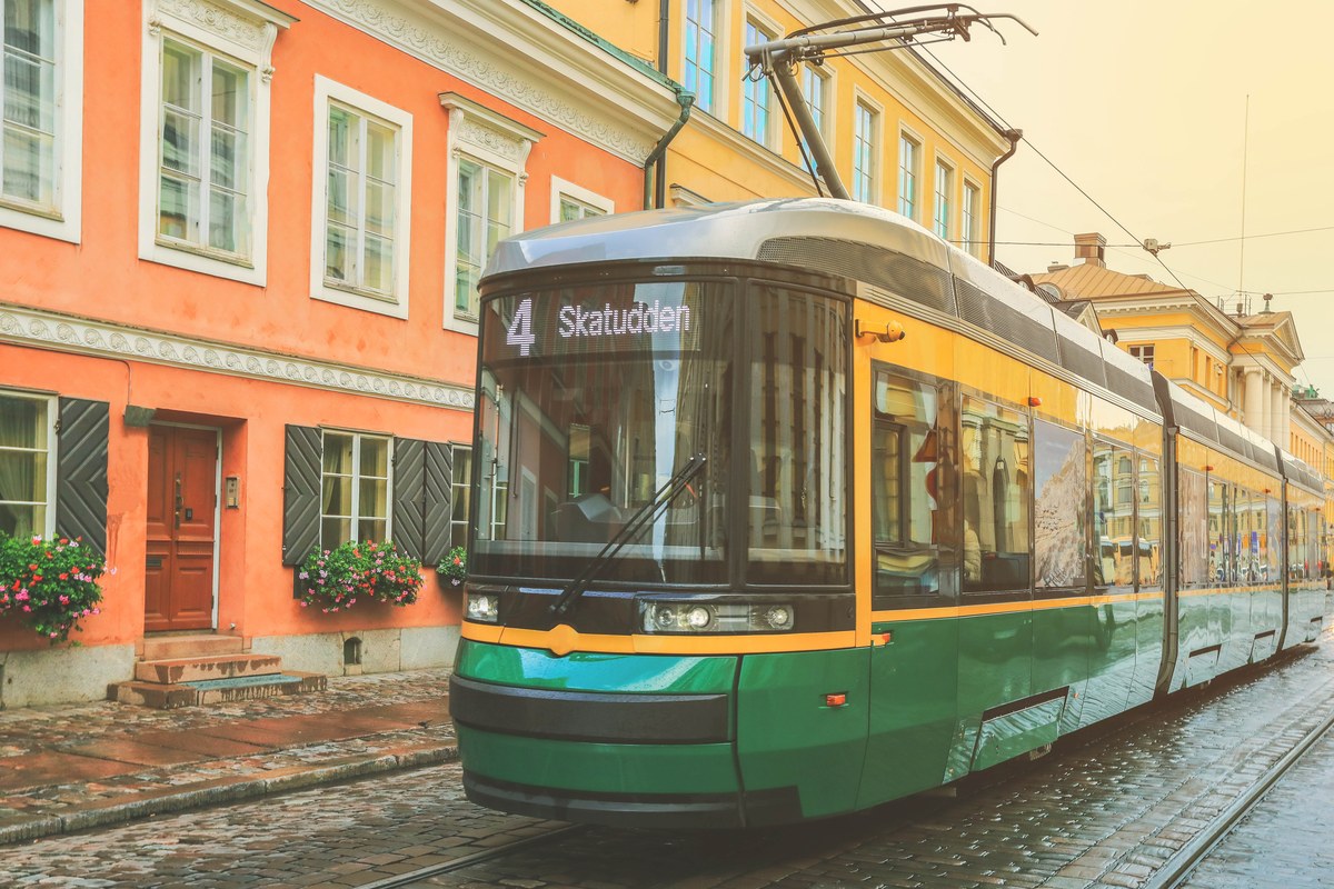 Green tram number 4 passing pastel buildings on a Helsinki street