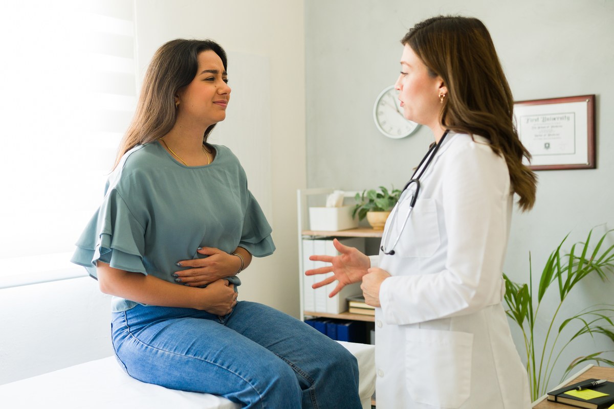 Woman in a grey top talking with a female doctor in a white coat in a clinic
