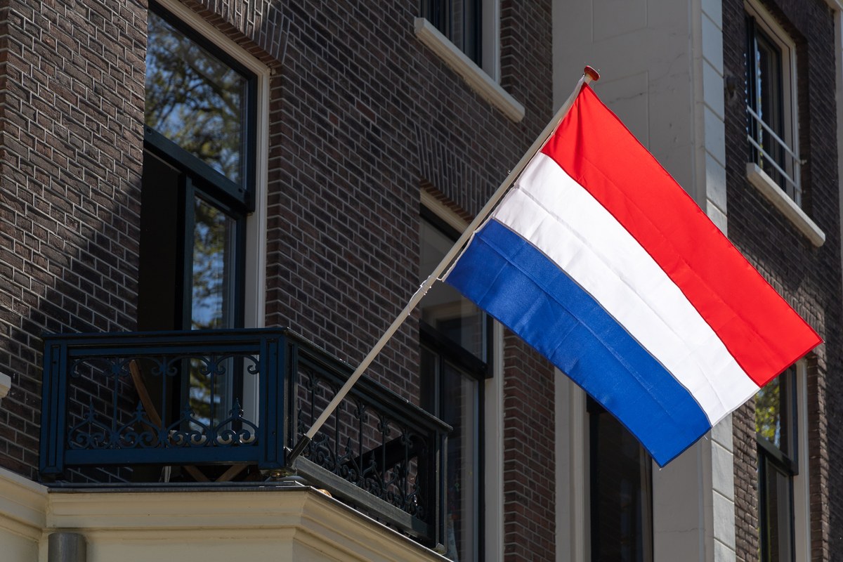 Dutch flag flying from a dark brick building with a balcony