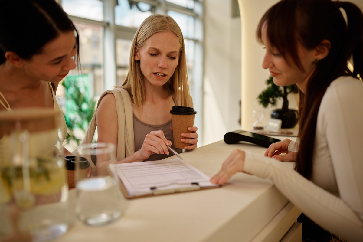 Woman signing a form at a reception desk with an employee