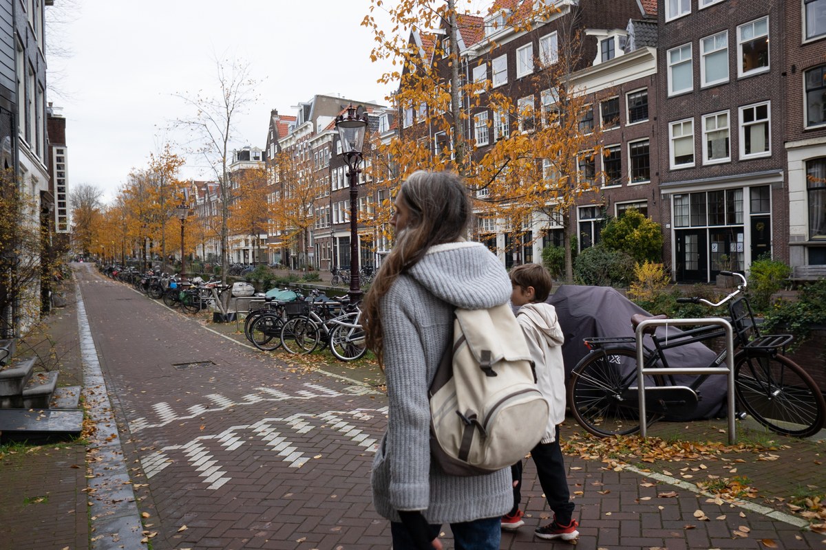 Mother with a backpack and her son walking along an Amsterdam canal in autumn