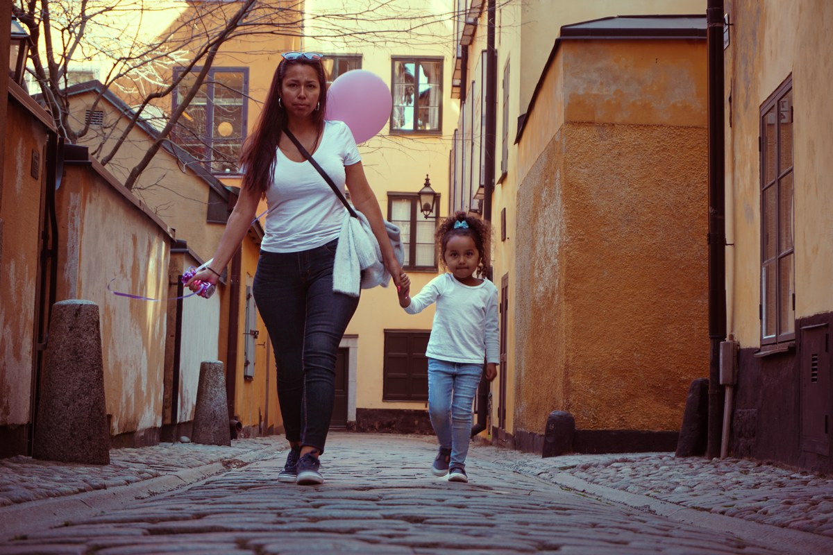 A woman and a girl holding hands walk down a cobbled street in Stockholm's old town