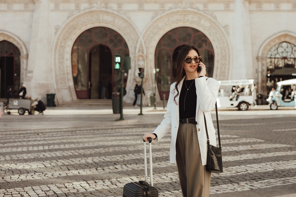 Woman with a suitcase on the phone outside Rossio station in Lisbon