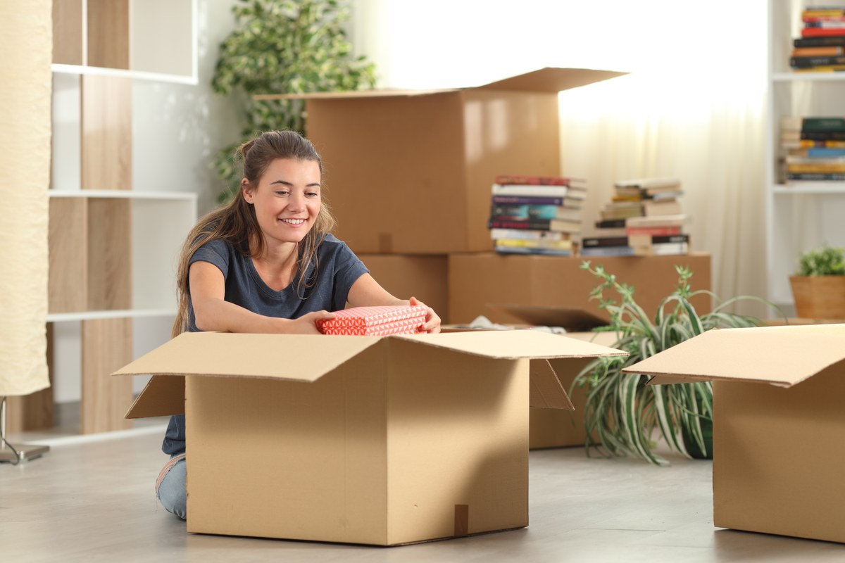 Smiling woman unpacking cardboard boxes in a new flat