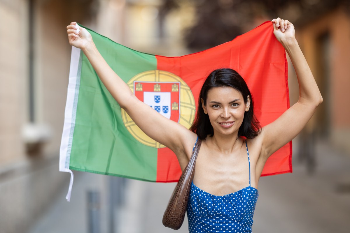 Smiling woman holding up a Portuguese flag on a city street