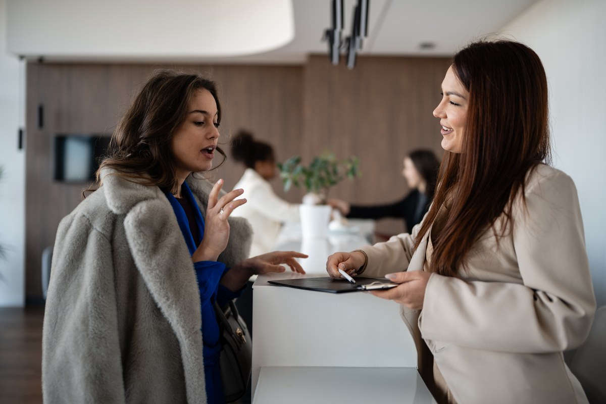 Woman talking with a receptionist at a hotel front desk